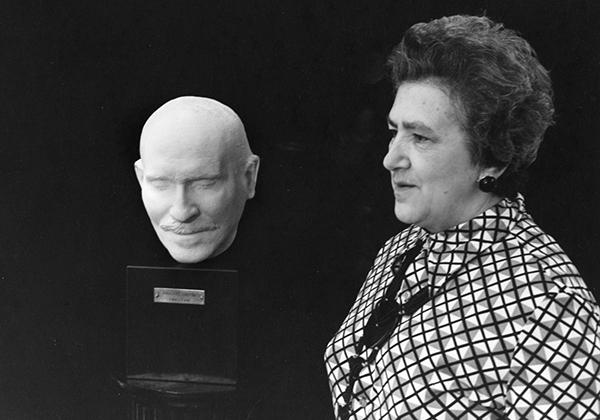 woman standing next to plaster bust of man's head